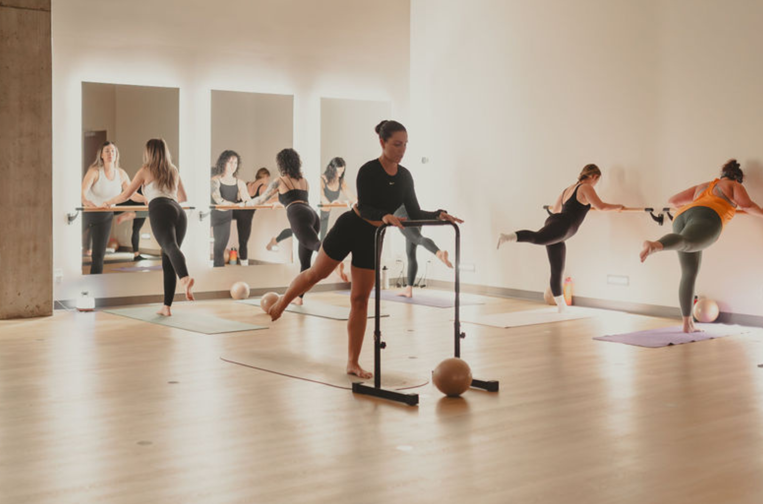Six femmes en train de pratiquer durant un cours de barre fitness.
