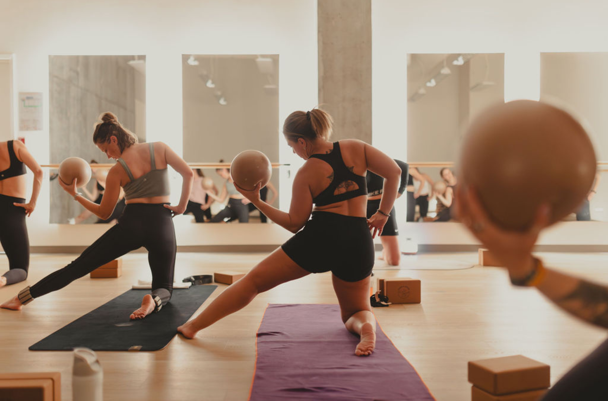 Des femmes tenant chacune un ballon durant un cours de Pilates chaud d'Espace Althéa.