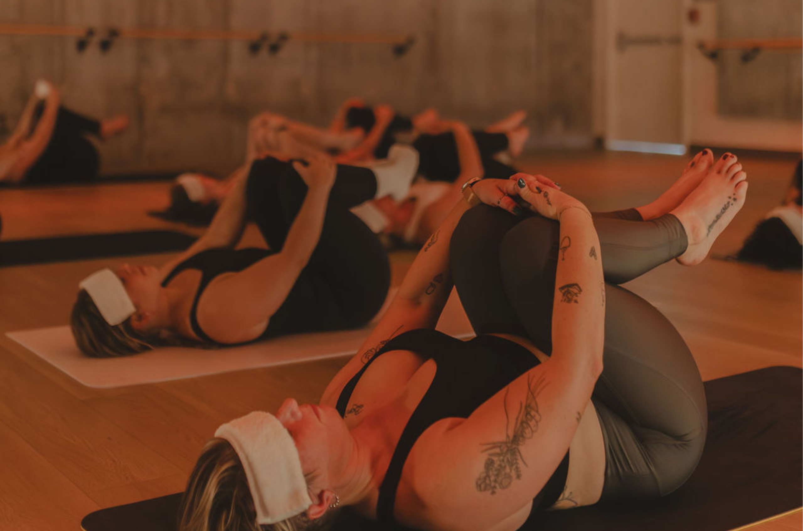Plusieurs femmes avec une serviette sur le front, en position de l'enfant, durant un cours de yoga chaud sur la Rive-Sud.